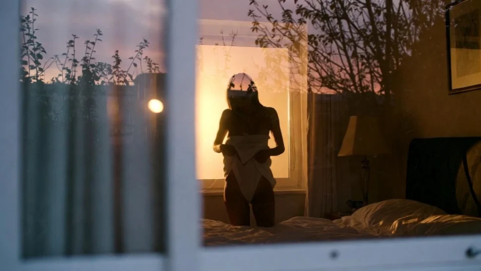 a woman undressing at night seen from window